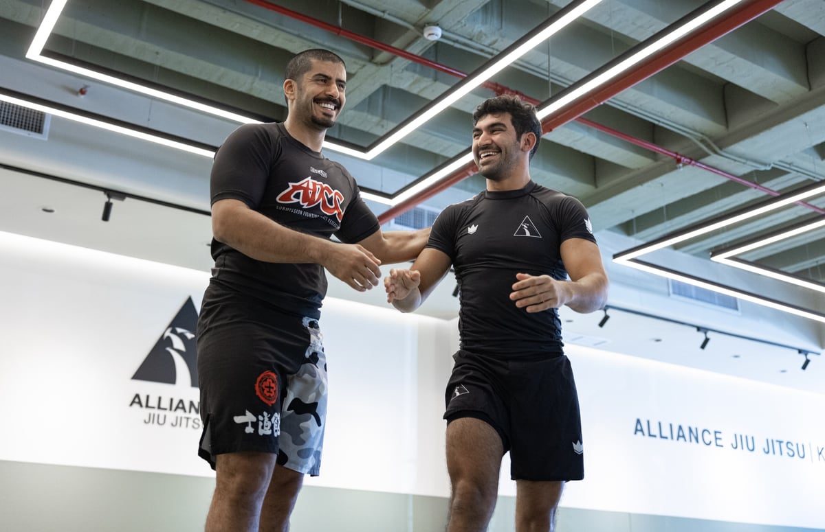 Two practitioners smiling and shaking hands after training at Alliance Kuwait